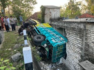 Kondisi dumptruk yang gagal nanjak dan jatuh menimpa bangun rumah warga