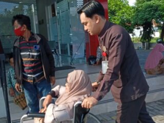Caption Foto: Petugas keamanan Klinik Mata Sampang, Yusuf Faisal Amin, tampak membantu seorang pasien lansia dengan mendorong kursi roda sebagai wujud pelayanan humanis di fasilitas kesehatan.