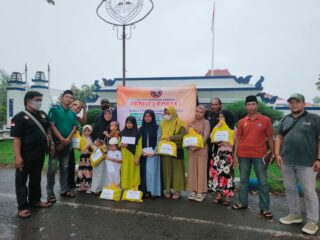 Caption Foto: Anggota Aliansi Wartawan Sampang (AWAS) menyerahkan santunan kepada anak yatim di Alun-Alun Trunojoyo, depan Pendopo Bupati Sampang, meski diguyur hujan dalam suasana Ramadhan.