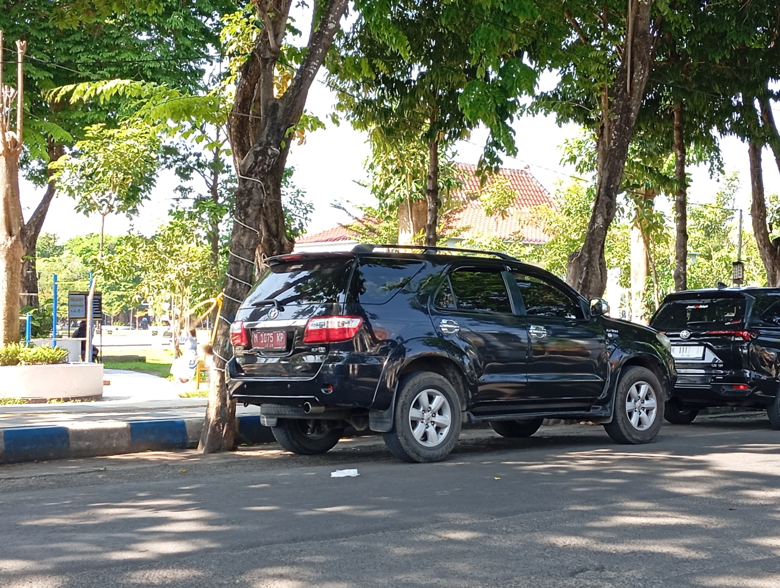 Caption Foto Mobil dinas jenis Toyota Fortuner bernomor polisi merah M 1075 NP terlihat terparkir di kawasan Alun-Alun Trunojoyo Sampang saat diduga digunakan untuk kepentingan pribadi bersama keluarga. Keberadaan kendaraan dinas tersebut menuai sorotan publik karena dinilai bertentangan dengan aturan penggunaan aset negara.